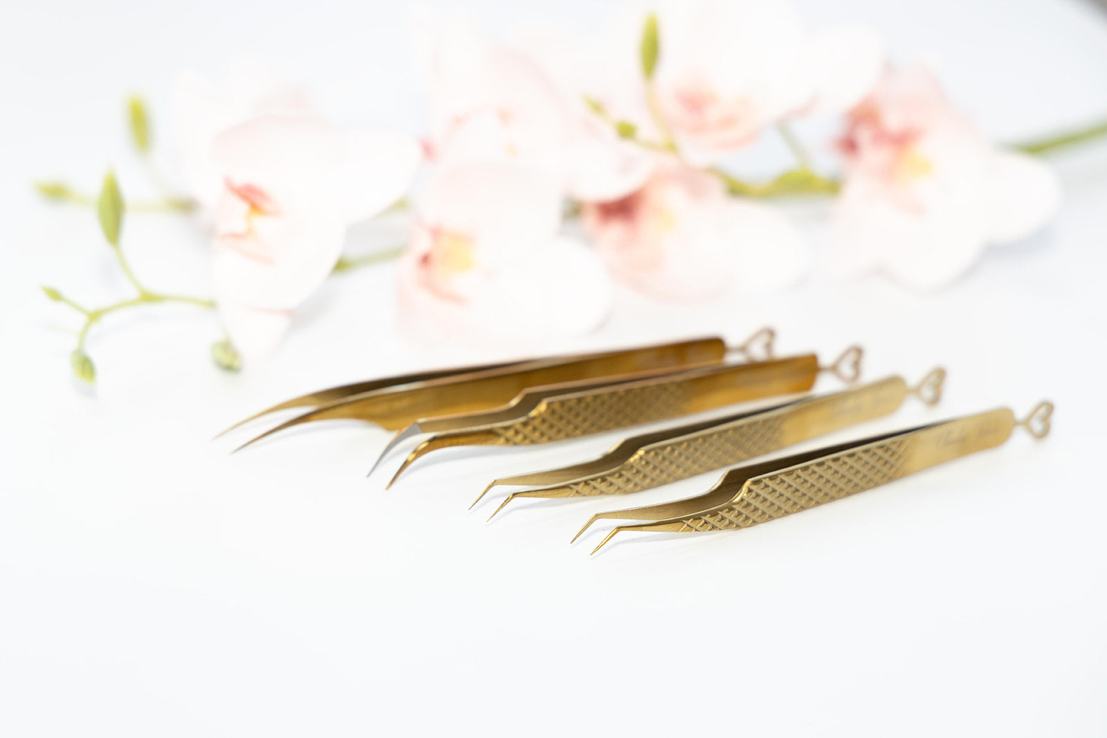 Set of gold tweezers on a white background with floral elements